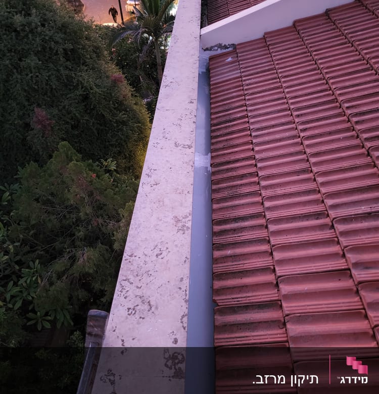 גג רעפים אדומים עם מרזב בטון בצד